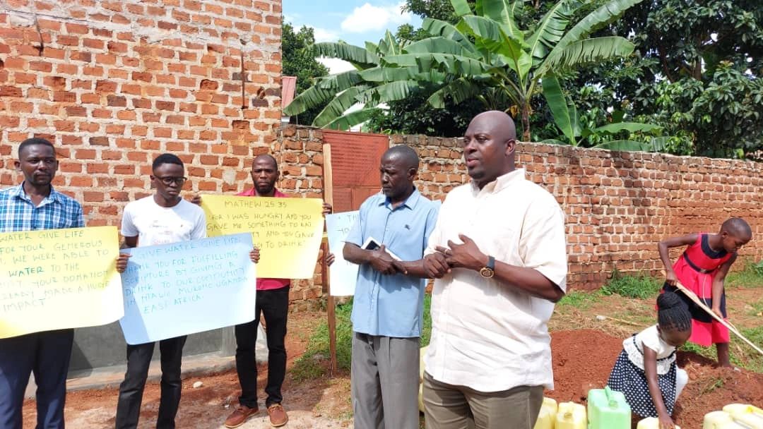 The Ntawo-Mukono community gathered at the build site with thank-you signs.
