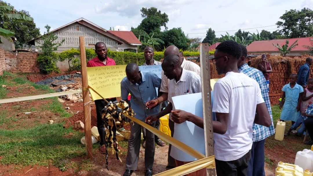 Community members cutting a ribbon to open the new water system in Ntawo-Mukono, Uganda.