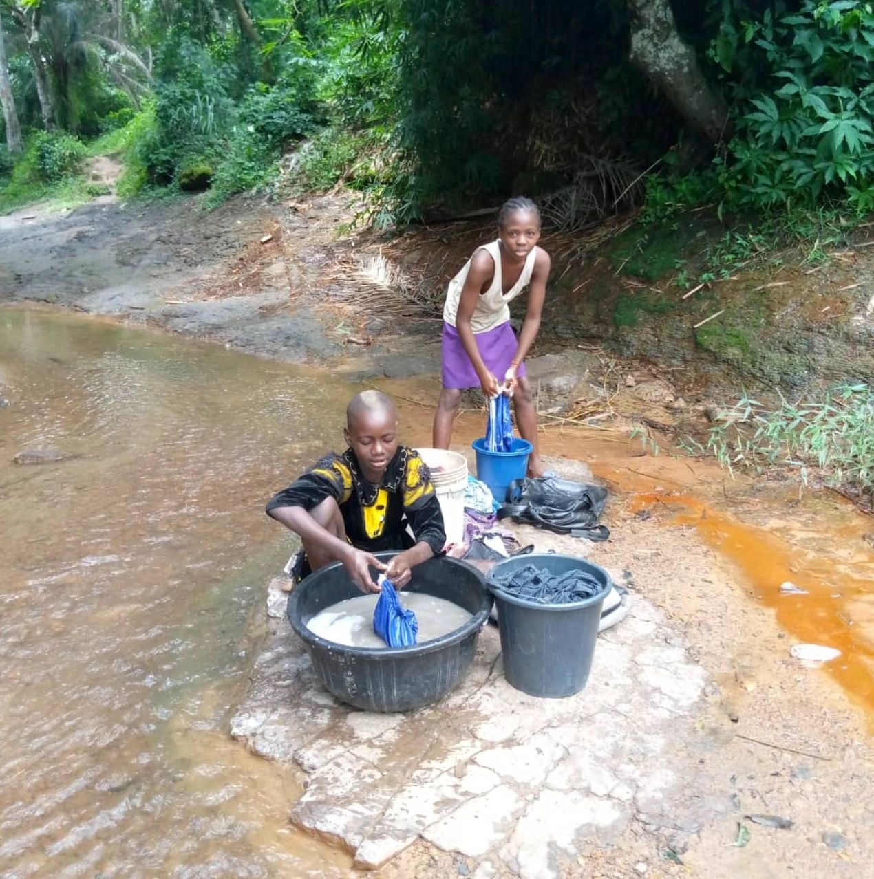 A child at a contaminated water source, the kind a community well replaces.